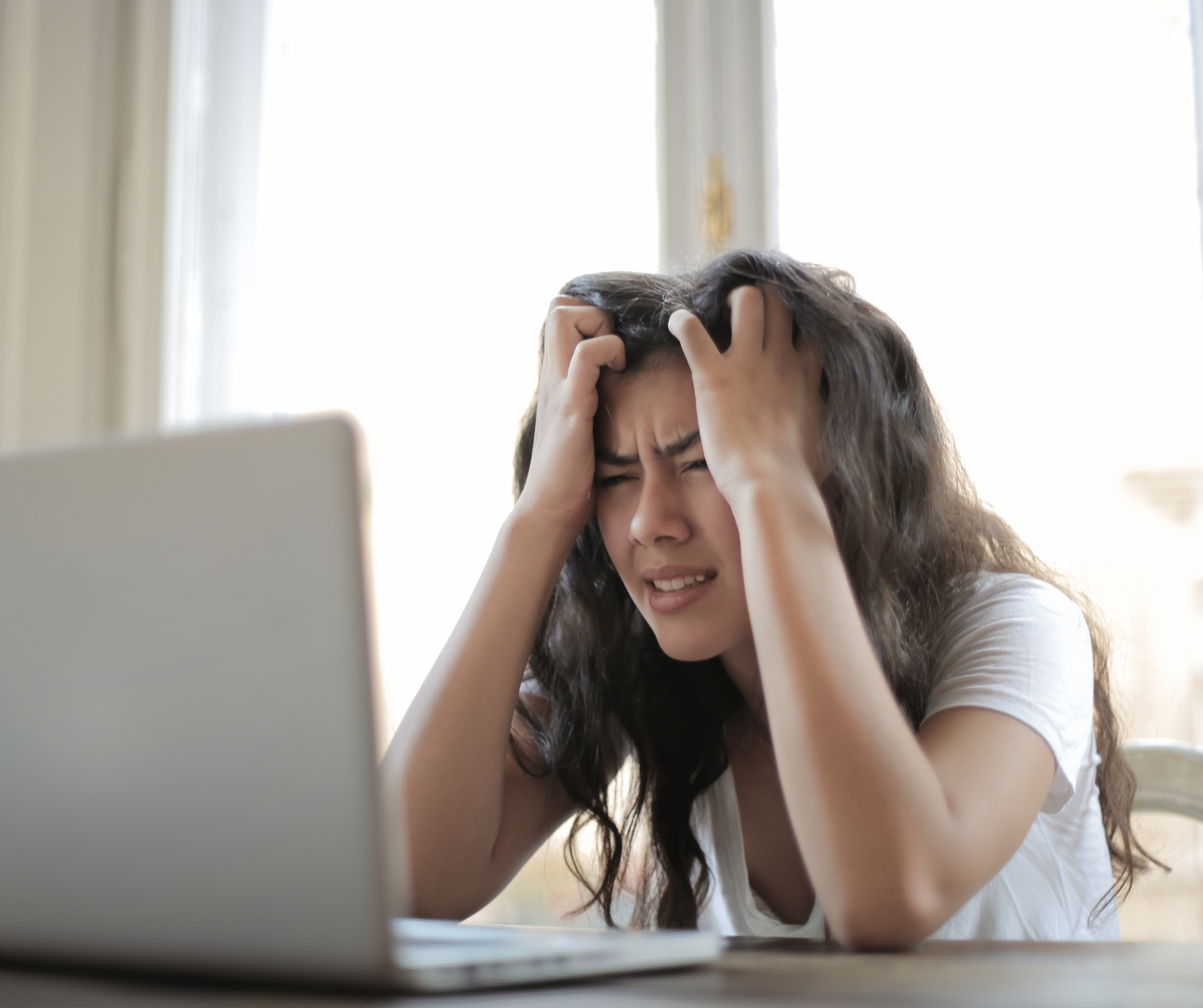 Ayurveda stress relief treatment Stressed young woman holding her head in frustration while working on a laptop