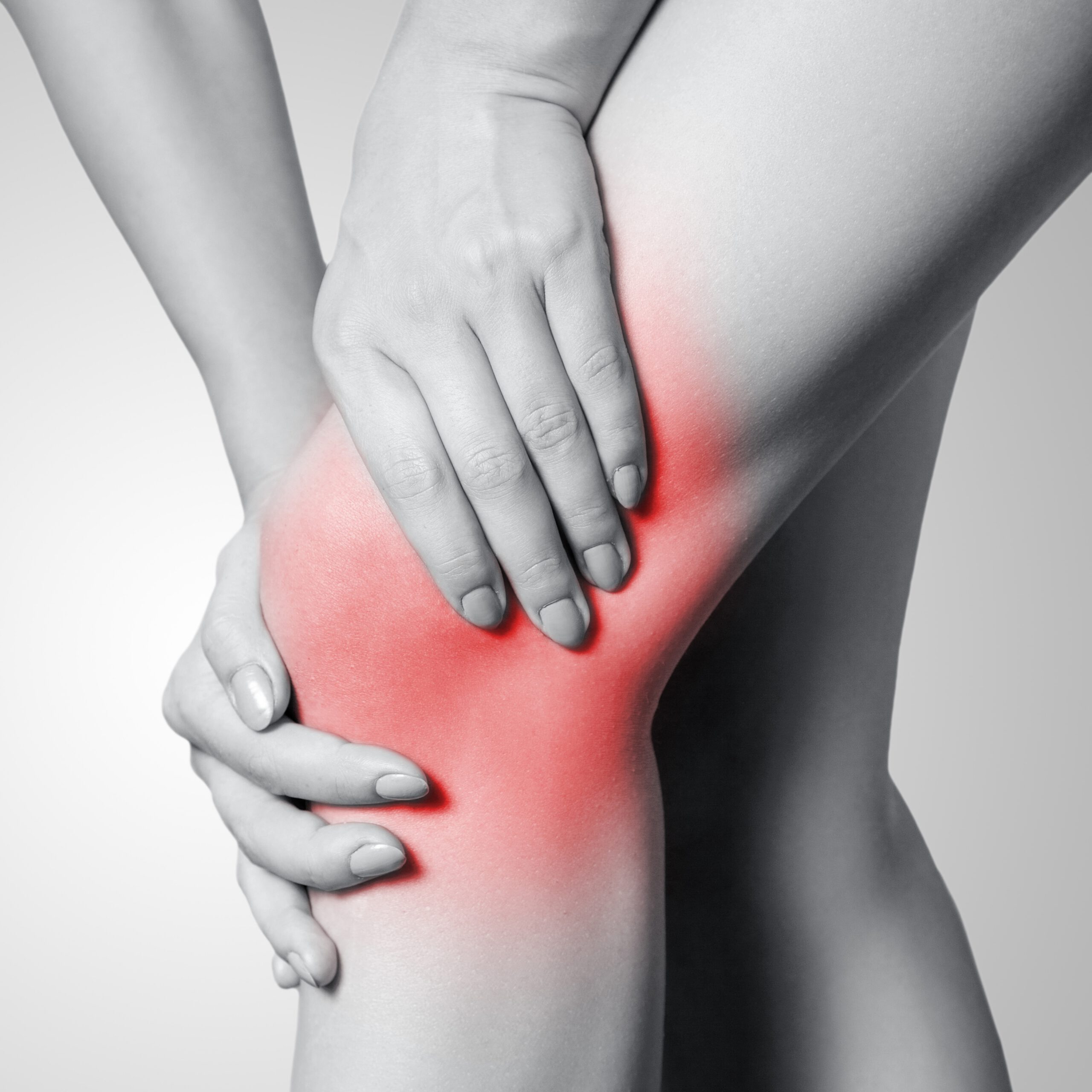 How Ayurveda Approaches Chronic Inflammation in Autoimmune Rheumatoid Arthritis The image shows a person clutching their knee with both hands, indicating pain or discomfort. The area around the knee is highlighted in red, symbolizing inflammation or joint pain. The rest of the image is in grayscale, which draws attention to the affected area. This visual suggests a condition such as arthritis, injury, or chronic joint issues. It is often used to depict musculoskeletal pain or to promote joint health awareness and treatments.
