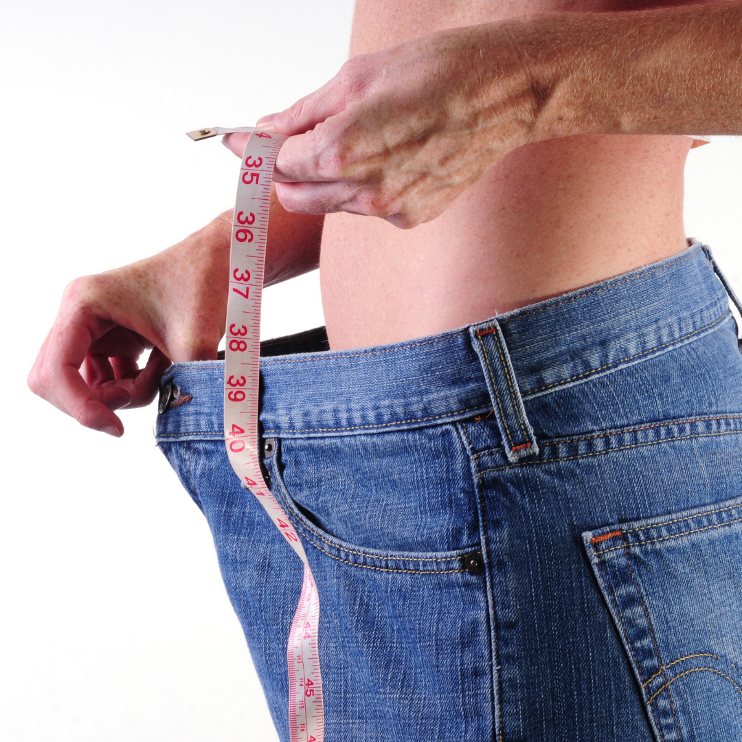Person showing weight loss by measuring waistline, symbolizing Panchakarma treatment for natural weight management in Ayurveda.